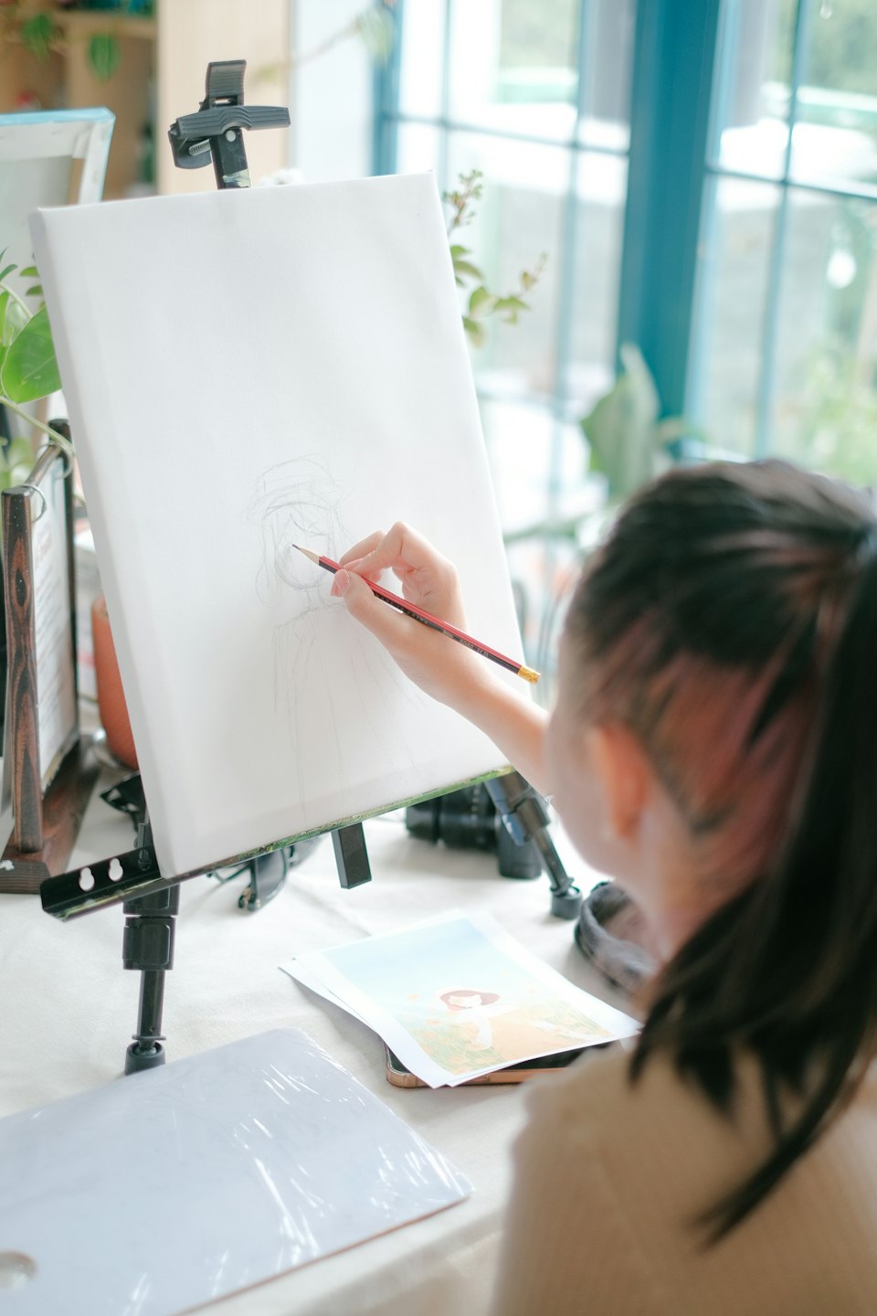 An artist sketches a portrait on a canvas at an easel.